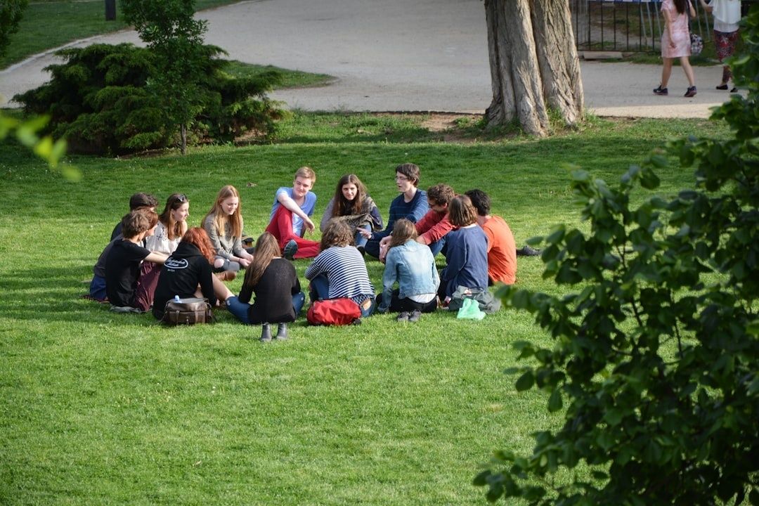 Ungdomar sitter i en samtalscirkel på en gräsmatta i en park